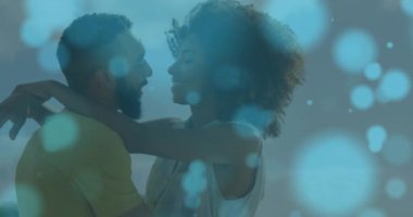 Deniz kenarında kucaklaşan melez çiftin üzerindeki ışık lekelerinin canlandırması. Yaşam tarzı, doğa ve dijital arayüz konsepti dijital olarak oluşturulmuş video.