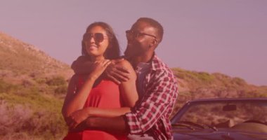 Deniz kenarında arabaya sarılan melez çiftin üzerine açık gölgenin animasyonu. Yaşam tarzı, doğa ve dijital arayüz konsepti dijital olarak oluşturulmuş video.