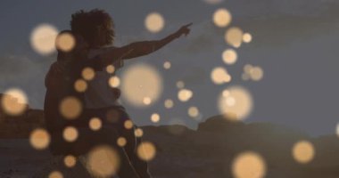 Deniz kenarında kucaklaşan melez çiftin üzerindeki ışık lekelerinin canlandırması. Yaşam tarzı, doğa ve dijital arayüz konsepti dijital olarak oluşturulmuş video.