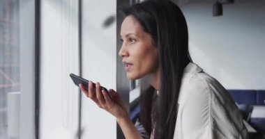 Çift ırklı iş kadınının akıllı telefondan konuşması üzerine dönen dünya ve verilerin animasyonu. Küresel iş ve dijital arayüz kavramı dijital olarak oluşturulmuş video.