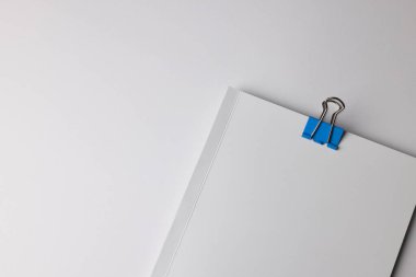 Beyaz çarşafların üzerinde mavi bir ataç, fotokopi alanı da var. Minimalist bir ortamda ele geçirilen temel ofis malzemeleri organizasyonu vurguluyor.