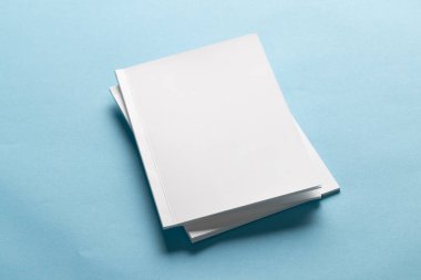 Mavi arka planda boş beyaz kitaplar, kopyalama alanı olan. Kapak tasarımlarını veya markalaştırma sunumlarını göstermek için ideal.
