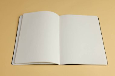 Açık, boş bir defter bej bir yüzeyde, kopyalama alanı var. Eğitim ayarları için idealdir, defter yaratıcı ifade veya not almaya davet eder.