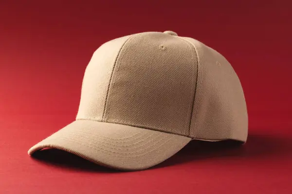 stock image A beige baseball cap is presented against a red background, with copy space. Its simplicity and the contrast of colors make it stand out, ideal for showcasing fashion accessories or custom branding designs.