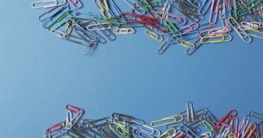 Renkli ataçlar mavi bir arkaplana saçılmış, fotokopi alanı var. Bu düzenleme ofis işi, organizasyon veya okul malzemeleri ile ilgili konular için idealdir..