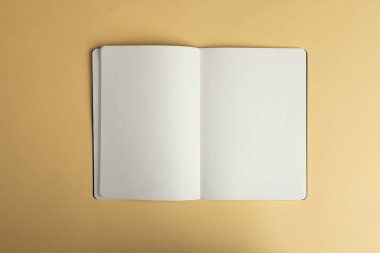 An open blank notebook lies on a beige surface, with copy space. Ideal for a minimalist setup, the notebook invites creative writing or note-taking. clipart