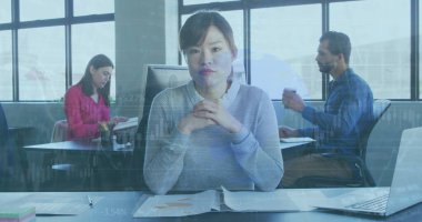 Çeşitli meslekdaşlar işe odaklanırken, Asyalı kadın önde. Kısa siyah saçları var, açık renk kazak giyiyor, düşünceli görünüyor. Kafkasyalı kadın kitap okuyor ve Orta Doğulu adam dizüstü bilgisayar kullanıyor.