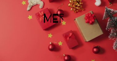 Kırmızı arka planda Noel süsleri üzerine Mutlu Noeller metni animasyonu. Noel, şenlik, kutlama ve gelenek konsepti dijital olarak oluşturuldu.