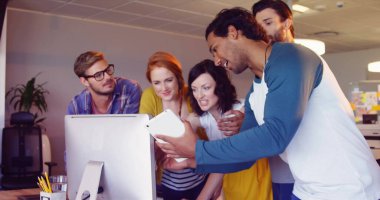 Kafkas ve melez meslektaşlar da dahil olmak üzere arkadaşlar bilgisayara bakıyorlar. Parlak bir ofiste fikirlerini paylaşıyorlar, takım çalışmasını gösteriyorlar.