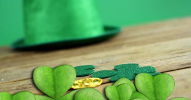 Image of st patrick's day shamrock and green hat on green background. St patrick's day, irish tradition and celebration concept, digitally generated image. clipart