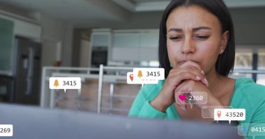 Orta renkli melez bir kadın dizüstü bilgisayar ekranına bakıyor. Düz siyah saçları, açık renk makyajı var ve üzerinde deniz mavisi bir bluz var.