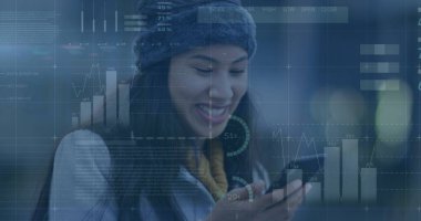 Şapkalı genç bir melez, akıllı telefona bakıyor. Uzun siyah saçları, sıcak bir gülümsemesi var ve kışlık giysiler giyiyor.