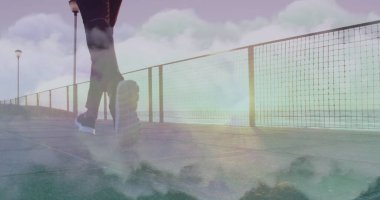 Sahilde koşan Afrikalı Amerikalı bir adamın üzerindeki bulutların görüntüsü. sağlık ve zindelik kavramı, dijital olarak üretilen görüntü.