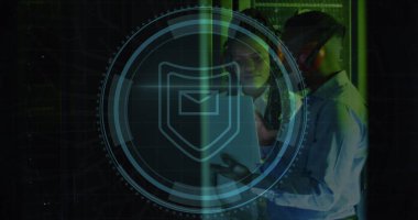 Sunucu odasında dizüstü bilgisayar kullanan Afro-Amerikan erkek ve kadın mühendis üzerindeki kalkan ikonu. Siber güvenlik ve iş veri depolama teknolojisi