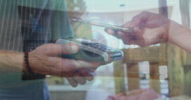 Kafkas meslektaşı ödeme terminali üzerinde akıllı telefon tutuyor. Açık tenli, sarı saçlı ve günlük kıyafetler giyiyor.