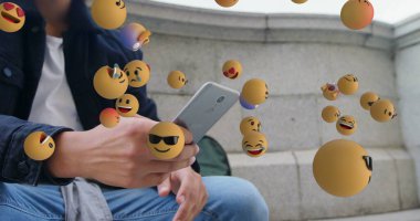 Çift ırklı, kıvırcık saçlı, akıllı telefon kullanan bir adamın üzerinde birden fazla yüzen emoji resmi. Dijital bileşik, çoklu pozlama, tepki, sosyal medya, soyut ve teknoloji kavramı.