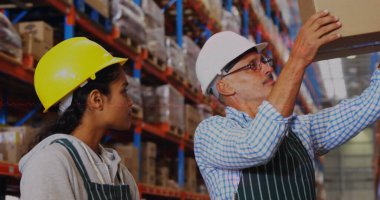 İspanyol iş arkadaşı ve Kafkas eğitmeni raflardaki eşyaları inceliyor. İkisi de kasklı, gözlüklü, sakallı, uzun saçlı.