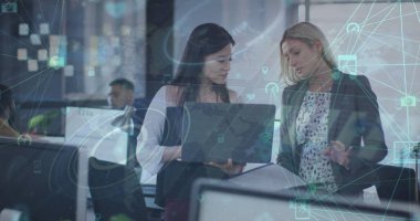 Ofiste dizüstü bilgisayarla tartışan iki farklı kadın üzerindeki dijital simgelerin görüntüsü. Küresel ağ ve iş teknolojisi kavramı