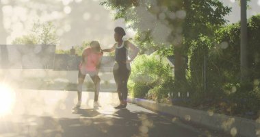 Afrika kökenli Amerikalı spor eğitmeni çift açık havada antrenman yapıyor. İkisi de güneşli parkta spor kıyafetleri ve spor ayakkabıları giyiyor.