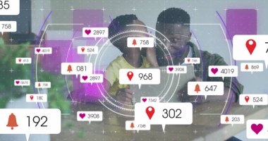 Afrikalı Amerikalı baba ve oğul renkli dijital grafiklere bakıyorlar. İkisinin de kısa siyah saçları var ve babam koyu renk gömlek giyiyor.