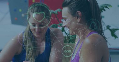 İki Kafkas iş ortağı, ikisi de kadın, akıllı telefona bakıyorlar. Açık kahverengi saçlı, at kuyruklu ve günlük spor kıyafetleri giyiyorlar.