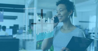 Kıvırcık saçlı melez bir meslektaşımız telefonda, elinde tabletle konuşuyor. Gri bir bluz giyiyor, açık kahverengi bir teni var ve ofisinde.