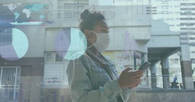 Akıllı telefon tutan Asyalı meslektaşım, ekrana bakıyor. Siyah saçlı, maske takıyor ve günlük kıyafetleri var.