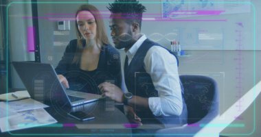 Kafkasyalı stajyer ve Afrikalı Amerikalı profesyonel laptoptaki verileri inceliyor. İkisi de genç, sarı saçlı kadın, kısa siyah saçlı adam.