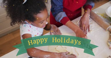 Image of happy holidays over happy african american daughter making cookies with mother. Christmas, tradition, celebration and family time concept digitally generated image. clipart