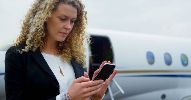 Beautiful businesswoman using mobile phone at terminal 4k clipart