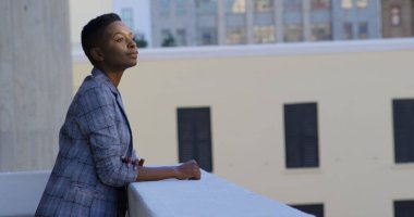 4K numaralı ofisin balkonunda düşünceli bir iş kadını duruyor.