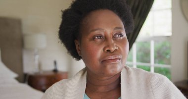 Düşünceli Afrikalı Amerikalı son sınıf öğrencisi kadın evde yatakta oturuyor. Koronavirüs salgını sırasında karantina karantinasına sosyal uzaklık