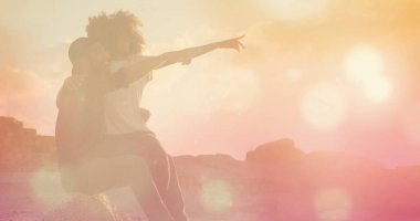 Renkli ışık efektleri olan kayaların üzerinde oturan çift. Romantik, açık havada, soyut, modern, gerçeküstü, doğa