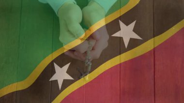 Elinde tespih, Saint Kitts ve Nevis bayrağını animasyon tarzında teslim et. Din, maneviyat, dua, kültür, inanç, maneviyat
