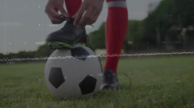 Futbolcu çimenlik alanda dijital veri animasyonuna ayakkabı bağlıyor. atlet, spor, teknoloji, analitik, performans, fitness