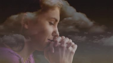 Elleri bağlı dua eden, bulutları olan ve arka plan animasyonunda haç olan bir kadın. Ruhani, inanç, ibadet, bağlılık, sükunet, dinsel