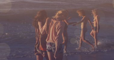 Sahilde yürüyen bir grup arkadaş, Bokeh Işıkları 'nın görüntüsü. Günbatımı, dinlenme, tatil, tatil, yaz, kıyı şeridi.