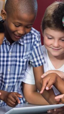 Tablet kullanarak ve gülümseyerek çeşitli okul çocukları üzerinde kalemlerin canlandırılması. okul ve eğitim kavramı dijital olarak oluşturulan video.