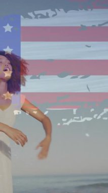 Sahilde elini kaldıran Afro-Amerikan kadının Amerikan bayrağının animasyonu. Vatanseverlik ve kutlama konsepti dijital olarak oluşturulmuş video.