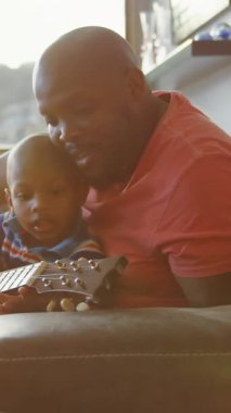 Mutlu Afro-Amerikan babasının oğluyla gitar çalması üzerine ışık noktalarının animasyonu. Babalar Günü ve kutlama konsepti dijital olarak oluşturulmuş video.