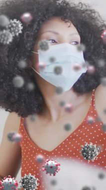 Yüz maskeli Afro-Amerikan bir kadın üzerinde virüs hücrelerinin canlandırılması. covid 19 pandemik konsept sırasında dijital olarak üretilen video.