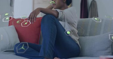 Kanepede oturan, yüzen çevre dostu animasyon ikonlarıyla çevrili biri. Sürdürülebilirlik, çevre, ekoloji, koruma, yeşil yaşam, enerji