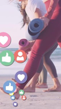 Sahilde yoga minderleri olan çeşitli kadınlar üzerinde medya simgeleri oluşturuluyor. Sosyal medya ve iletişim arayüzü kavramı dijital olarak oluşturulmuş video.