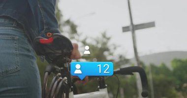 Bisiklet tutan, sosyal medya bilgilendirme ikonlarının animasyonuyla çevrili olan kişi. Teknoloji, bildirimler, dijital, iletişim, bağlantı, etkileşim