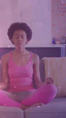 Afrika kökenli Amerikalı bir kadının evde meditasyon ve yoga yapması üzerine ışıklandırma animasyonu. dünya meditasyon günü ve dijital olarak üretilen video konsepti.