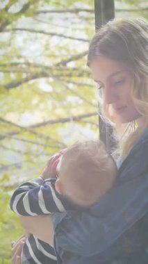 Beyaz anne ve bebek süt içerken gün ışığında ağaçların canlandırılması. Anneler Günü ve annelik kavramı dijital olarak üretiliyor..