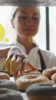 Asyalı kadın fırıncının çörekleri hazırlarken yeşil noktaların canlandırılması. Ulusal pasta günü ve dijital olarak üretilen video konsepti.