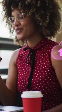 Akıllı telefon kullanan Afro-Amerikan iş kadını üzerindeki bulut simgelerinin canlandırılması. Sosyal medya ve iletişim arayüzü kavramı dijital olarak oluşturulmuş video.