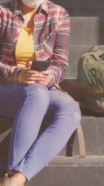 Akıllı telefon kullanarak yüz maskesi takan melez bir kadının üzerindeki ışık lekelerinin canlandırılması. Ulusal bisiklet iş günü için ve covid 19 salgın konsepti dijital olarak oluşturulan video sırasında kutlamak için.