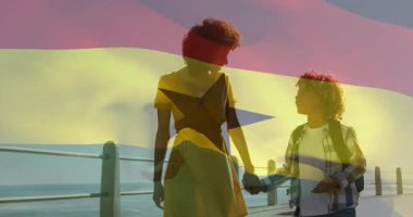 Okyanus kıyısında yürüyen, Gana bayrağı animasyonu ile anne ve çocuğu. Aile, ebeveynlik, bağlılık, plaj, seyahat, keşif